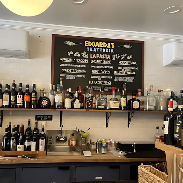 A chalkboard menu for Edoardo's Trattoria pasta dishes above a bar with bottles of wine and spirits.