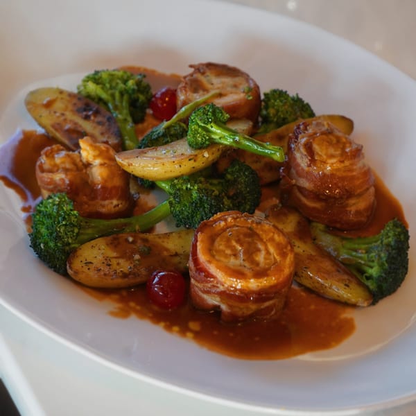Edoardo's Trattoria's bacon-wrapped medallions with roasted potatoes, broccoli, and cherry tomatoes in sauce.