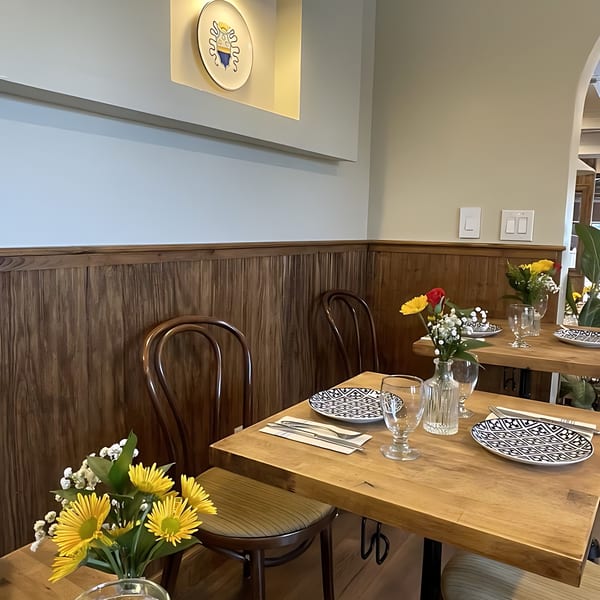 Edoardo's Trattoria dining room with wooden tables set with patterned plates and fresh flowers.