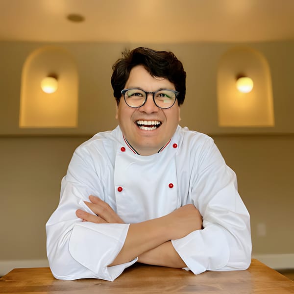 Edoardo's Trattoria chef, smiling with arms crossed, wearing glasses and a white chef's coat.