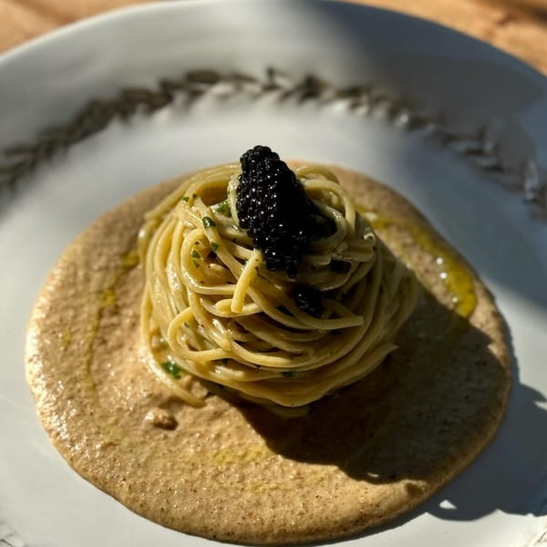 Edoardo's Trattoria's spaghetti with black caviar and a creamy sauce on a white plate.